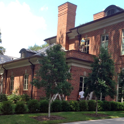A large brick house with trees and bushes.